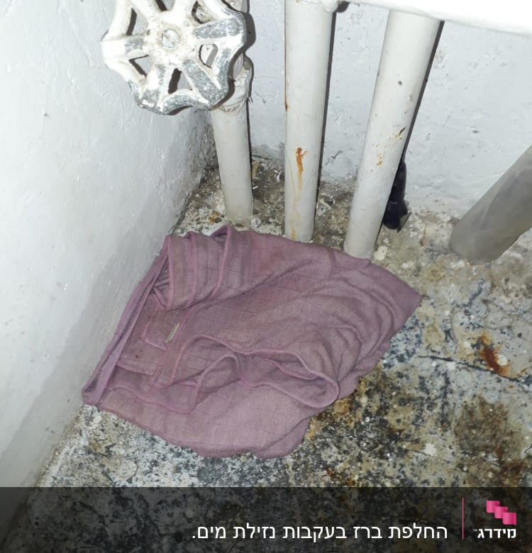 ברז ישן עם צינורות חלודים ומטלית סגולה